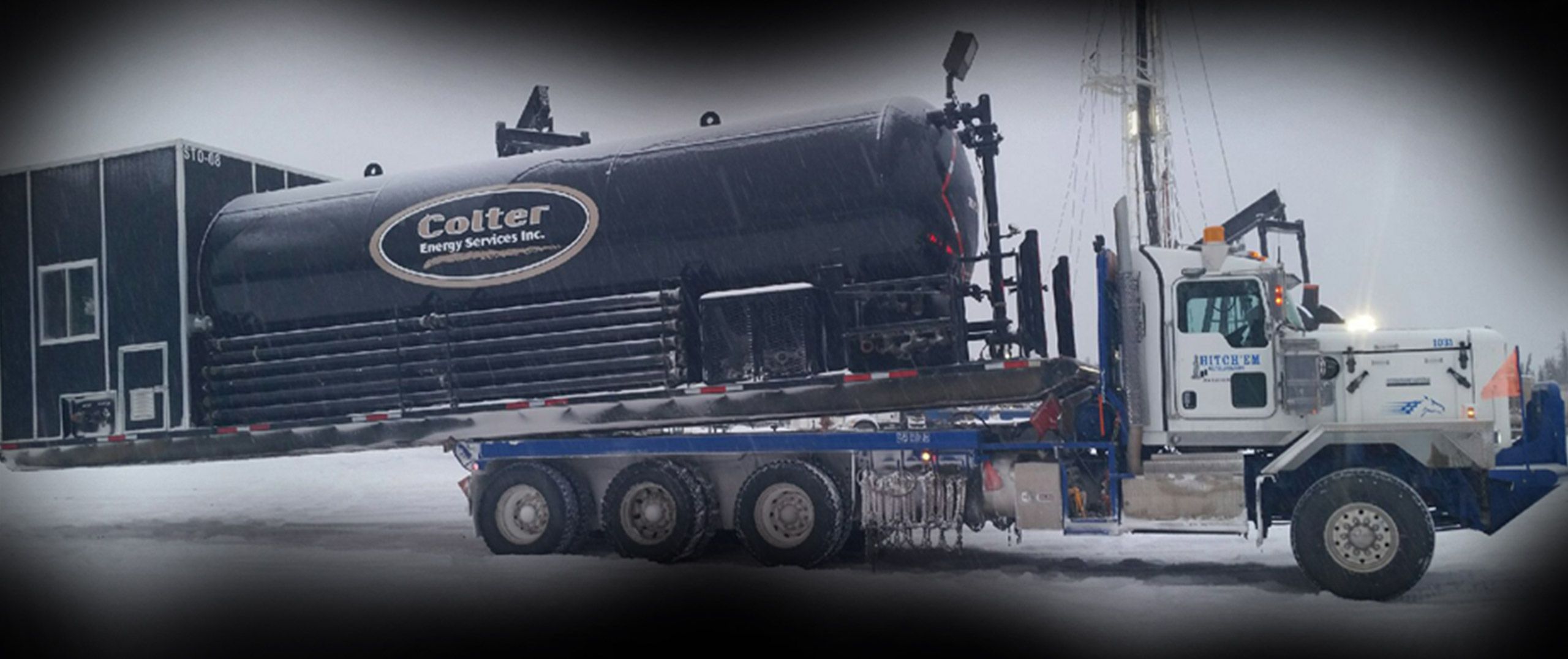 A Hitch'em bed truck hauling a loaded tank across the patch